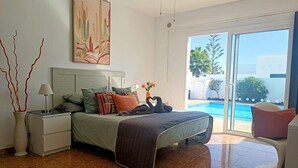 Ein Schlafzimmer mit Bett, Nachttischen, einer Lampe, einer Blumenvase und einem Gemälde.
