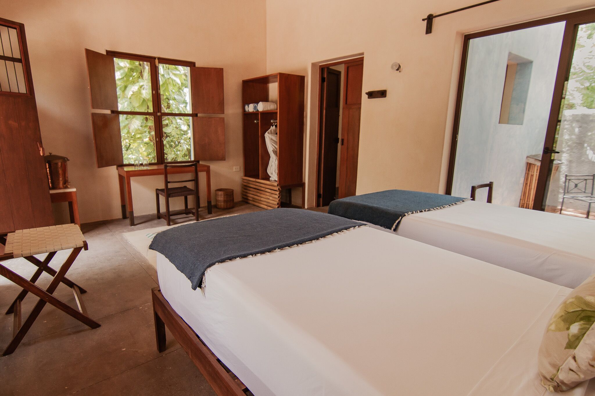 A room with two beds, a wooden desk, a chair, and a wardrobe.