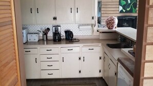 A compact kitchen with white cabinets, a coffee maker, and a sink. - Escape to Island Paradise - Clearwater Bay, L.O.T.W. (Clearwater Bay)