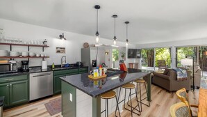 Une cuisine moderne dotée d’un îlot central, de tabourets de bar et d’un coin repas comprenant un canapé et des chaises.
