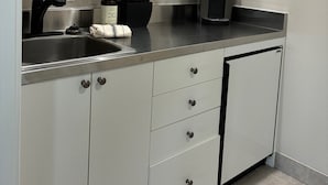A kitchen with white cabinets, a stainless steel sink, a microwave, and a coffee maker. - The Captain's Quarters located in Cape Charles, VA offers breathtaking views. (Cape Charles)
