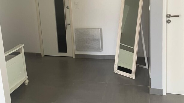 Une pièce avec une porte, un radiateur et un miroir appuyé contre le mur.