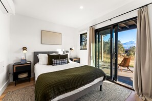 Une chambre dotée d’un grand lit, d’une table de chevet, d’une commode, d’une fenêtre offrant une vue agréable et d’une porte-fenêtre coulissante donnant sur un espace extérieur.