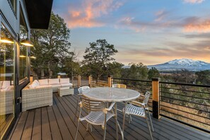 Relax on the spacious deck with a sofa, chairs, and table, taking in the breathtaking mountain view.