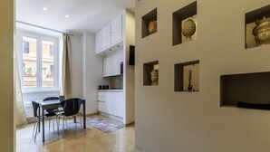 A modern kitchen with white cabinets, a dining area with a table and chairs, and decorative wall art.