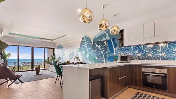 A modern kitchen with a view of the ocean, a dining area with a view, and a living area with a large plant. - Malkita Sol | Oceanview Paradise + Concierge Service (Isla Mujeres)