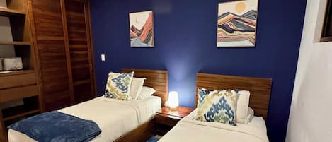 A hotel room with two beds, a wardrobe, and artwork on the walls.