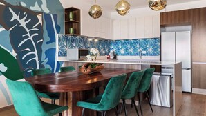 A modern kitchen with a central island, green chairs, and pendant lighting. - Malkita Sol | Oceanview Paradise + Concierge Service (Isla Mujeres)