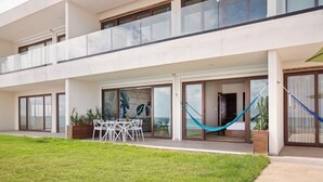 A modern building with a covered outdoor area, a dining table with chairs, and a hammock. - Malkita Sol | Oceanview Paradise + Concierge Service (Isla Mujeres)