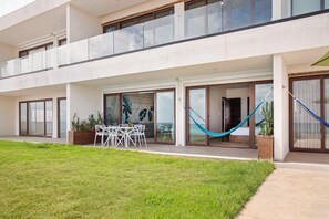 Un edificio moderno con un'area esterna coperta, un tavolo da pranzo con sedie e un'amaca.