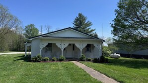A white single-story house with a porch, a driveway, and a lawn.