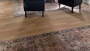 A living room with a sofa, two armchairs, a coffee table, and a rug.
