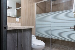 Un baño moderno con inodoro, espejo y cabina de ducha.