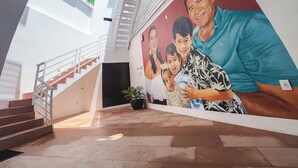 Un edificio moderno con una escalera, un mural de personas y una pared verde.