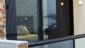 Un interior moderno con una puerta de vidrio que da a una habitación con un sofá y una planta.