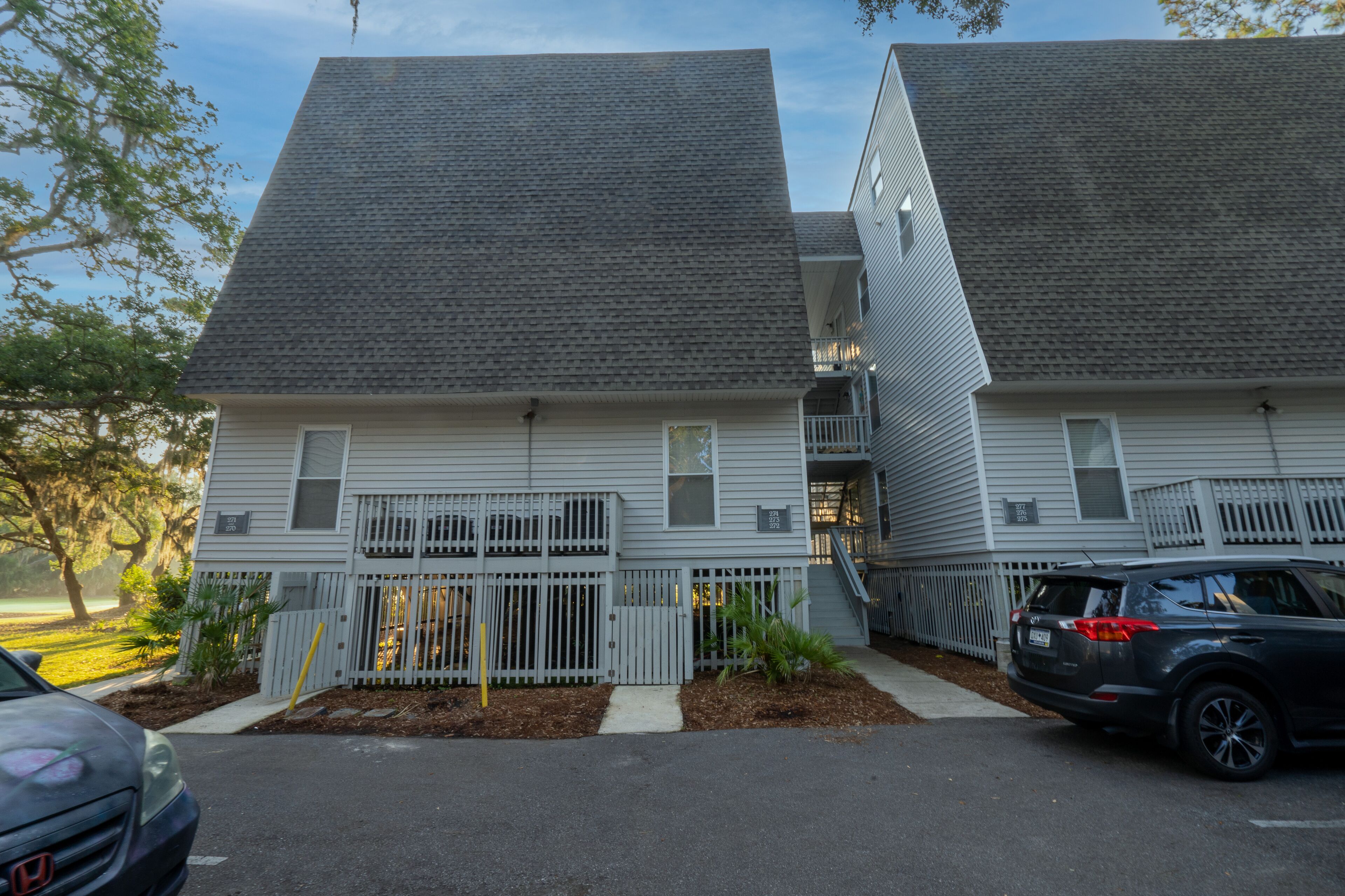 A two-story residential building with a grey roof and white siding.