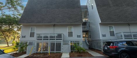 A two-story residential building with a grey roof and white siding.