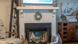A living room with a fireplace, a bookshelf, and a decorative mantelpiece.