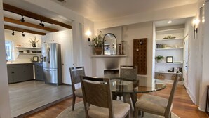 Una cocina moderna con refrigerador empotrado, armarios de madera y un comedor con mesa y sillas de vidrio.