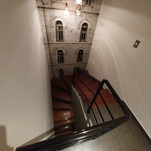 A staircase with a handrail leading to a building with multiple windows and a light fixture above. - Larcomar Luxury Penthouse (Miraflores)