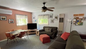A living room with a ceiling fan, a sofa, a TV, and a dining area with chairs and a table. - Go out on an Adventure! Relax & Unwind at our cozy & quiet location.Pet Friendly (Munising)