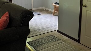 A room with a door, a coat rack, a clock, a window, and a couch. - Go out on an Adventure! Relax & Unwind at our cozy & quiet location.Pet Friendly (Munising)