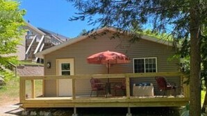 A single-story house with a fenced deck, a red umbrella, and a small table with chairs. - Go out on an Adventure! Relax & Unwind at our cozy & quiet location.Pet Friendly (Munising)