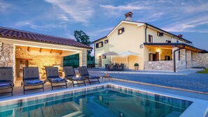 A poolside area with lounge chairs and a stone building with a tiled roof. - Rückzugsort am Meer mit Pool, nur Wenige Minuten vom Strand Entfernt (Trget)