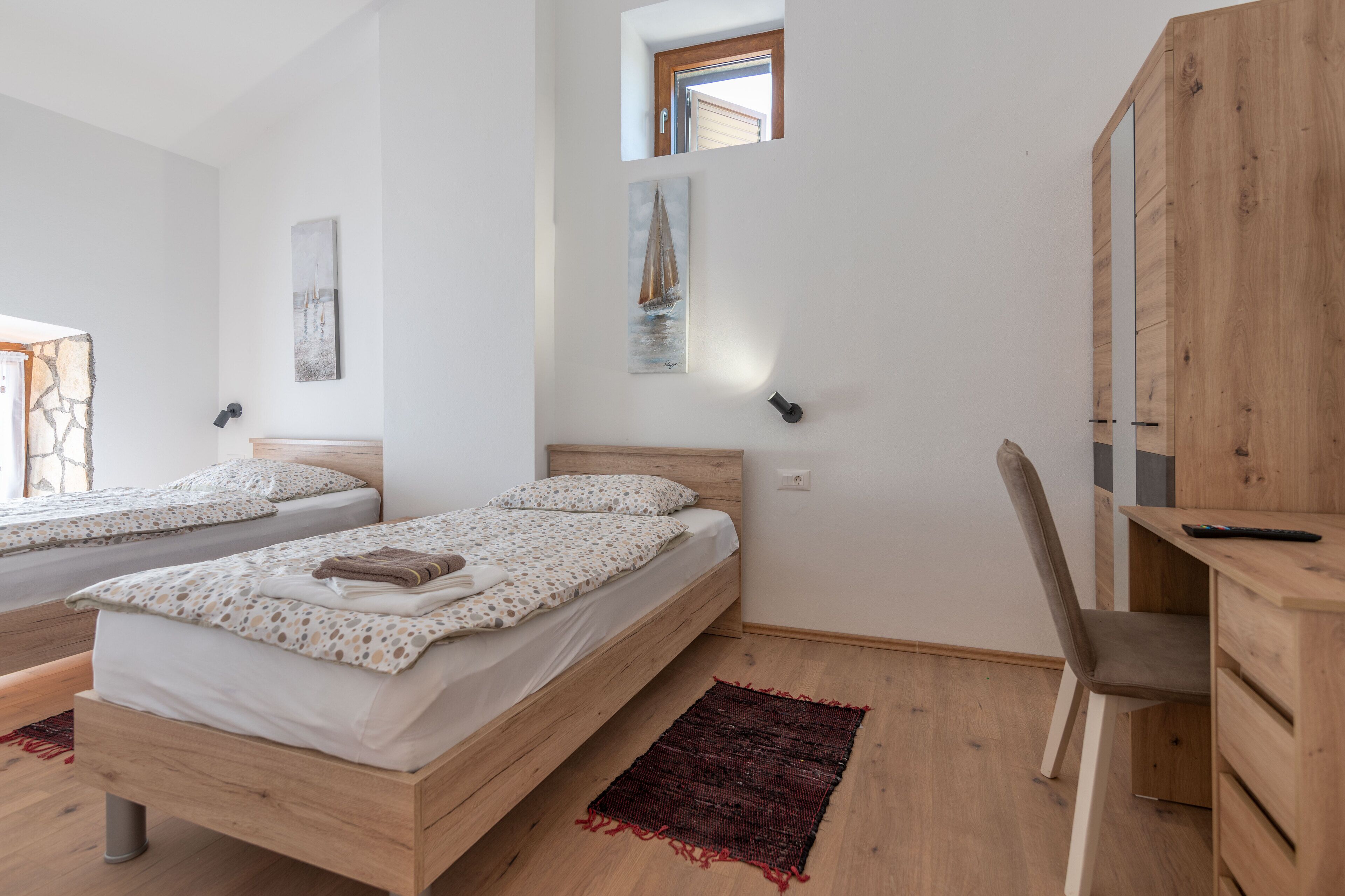 A bedroom with two beds, a wooden desk, and a chair.