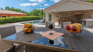 An outdoor patio with wicker furniture, a glass-top table, and a fruit bowl. - Rückzugsort am Meer mit Pool, nur Wenige Minuten vom Strand Entfernt (Trget)