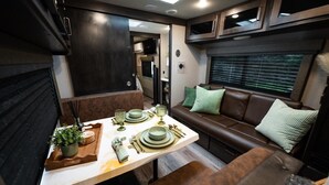 Interior compacto de una caravana con comedor, asientos y kitchenette.