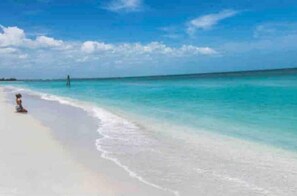 Een strand met helder turquoise water en wit zand.