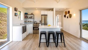 Una cocina moderna con una isla central, electrodomésticos de acero inoxidable y vistas al exterior.