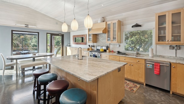 Una cucina moderna con un'ampia isola, mobili in legno e illuminazione a sospensione.
