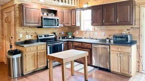 Una cocina con armarios de madera, microondas, estufa, pileta y tostadora.