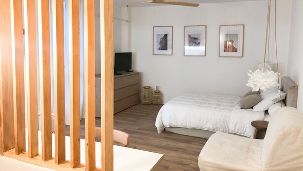 A bedroom with a bed, a dresser, a TV, and framed pictures on the wall. - Studio in the historic center (Ajaccio)