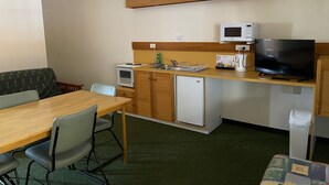 A compact kitchenette with a microwave, small refrigerator, and a TV. - Landsborough Lodge Motel (Barcaldine)