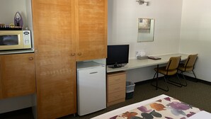 A compact hotel room with a wooden wardrobe, a microwave, a small refrigerator, a desk with a computer, and a chair. - Landsborough Lodge Motel (Barcaldine)