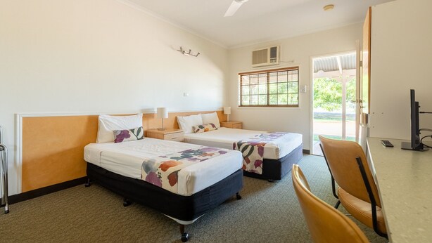 A hotel room with two beds, a desk, a chair, a ceiling fan, and a window with blinds. - Landsborough Lodge Motel (Barcaldine)