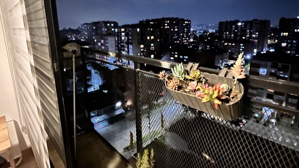 En balkon med udsigt over nattens bybillede, med gelænder og plantekasser.