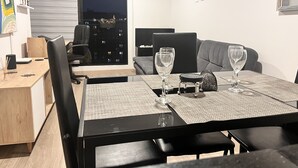 En moderne stue med et spisebord, to sofaer og udsigt over byen om natten.
