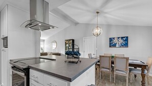 Una cocina moderna con una isla central, horno empotrado y campana extractora de acero inoxidable.