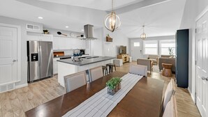 Una cocina moderna con una isla central, electrodomésticos de acero inoxidable e iluminación colgante.