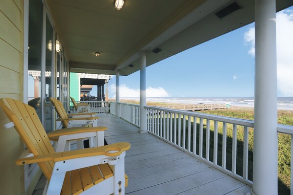 Enjoy the ocean view from this covered porch with a railing and comfortable seating.