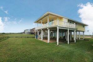 Enjoy stunning ocean views from the upper balcony of this beachfront house, featuring a covered porch and flat roof.