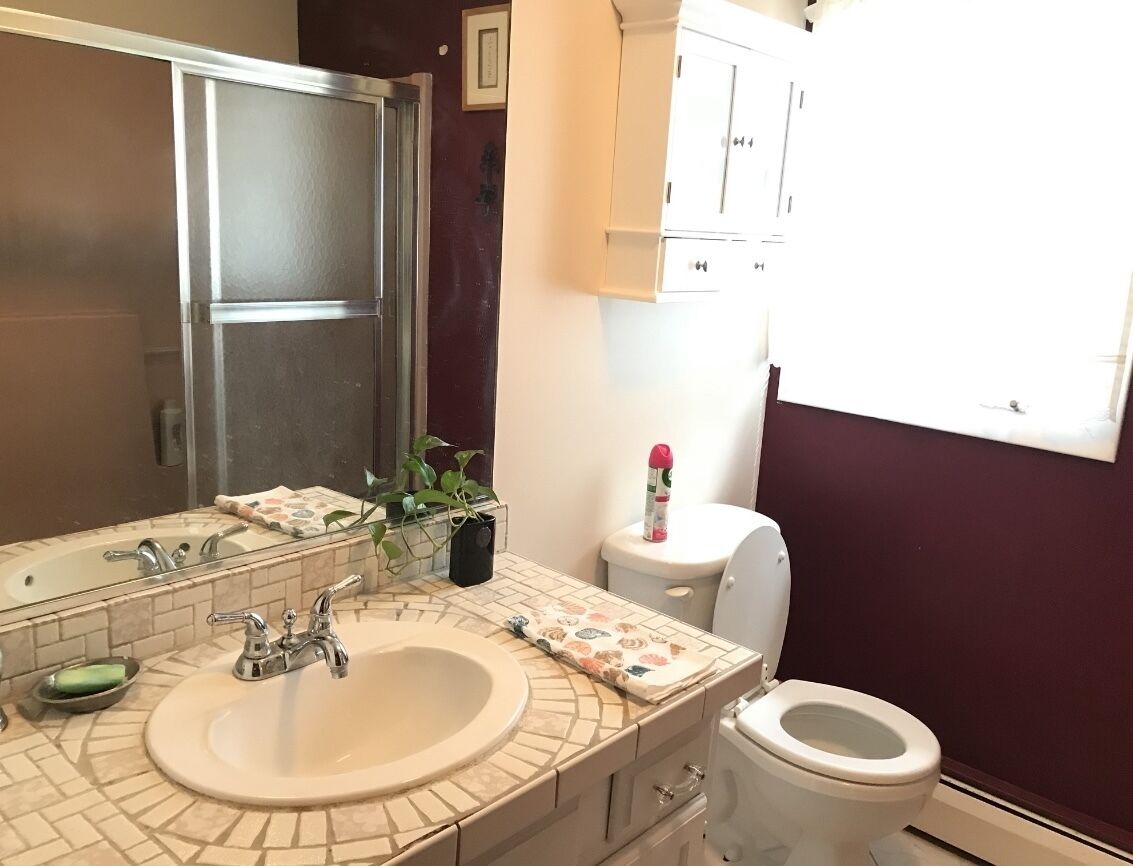 Un baño con lavabo, espejo, inodoro y armarios.