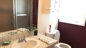 Un baño con lavabo, espejo, inodoro y armarios.