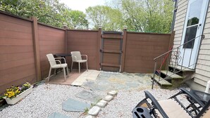 A backyard with a patio area, a wooden fence, a ladder, and outdoor furniture. - Spacious, comfortable rooms near beach & Newport (Middletown)