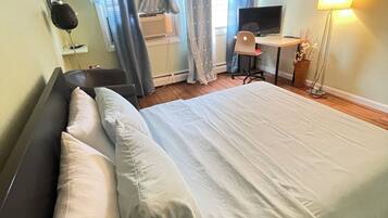 Una habitación de hotel con cama, escritorio, silla, televisor y lámpara.