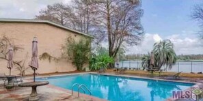 Relax by the pool surrounded by a patio area with outdoor furniture and scenic views.